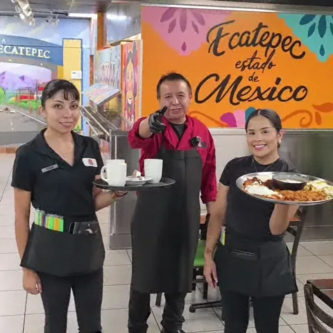 The Camacho's Restaurant team holding breakfast charolas in front of their Ecatepec, Estado de México mural