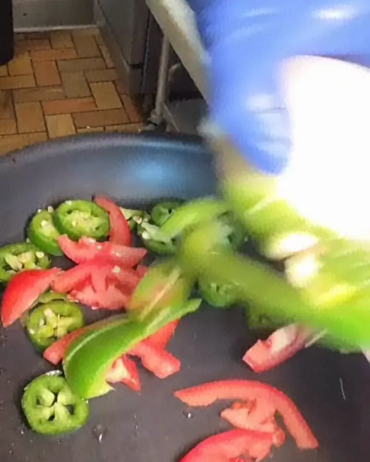 Peppers, onion and tomato going into the pan in Camacho's kitchen